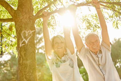 Glückliches Senioren-Paar unter einem Baum: Schlaganfallvorsorge hilft, länger etwas vom Leben zu haben 