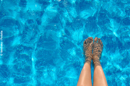Frau hält ihre Beine ins Wasser: Bei Hitze leiden die Venen. Mit unseren Venen-Tipps kommen Sie gut durch den Sommer. 